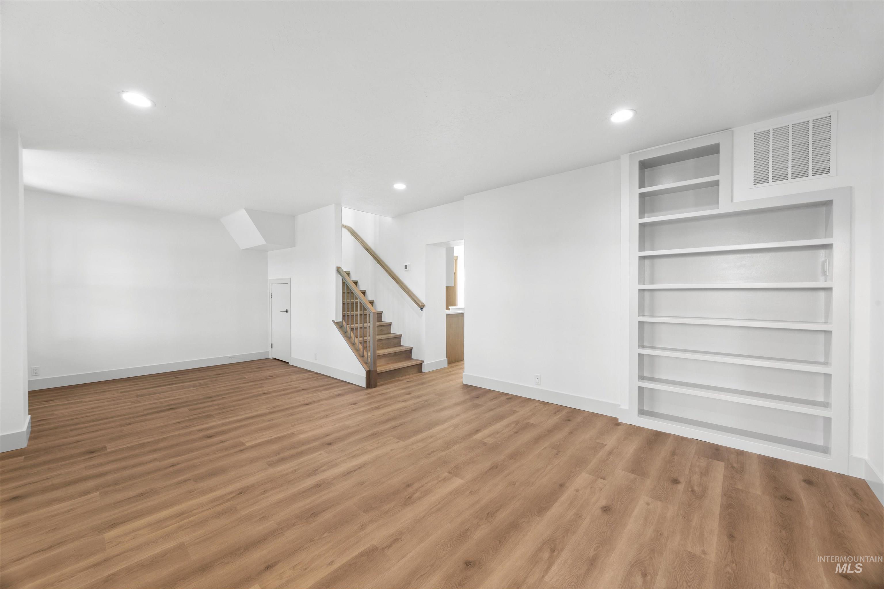 Basement with light wood-style floors, stairway, built in features, and recessed lighting