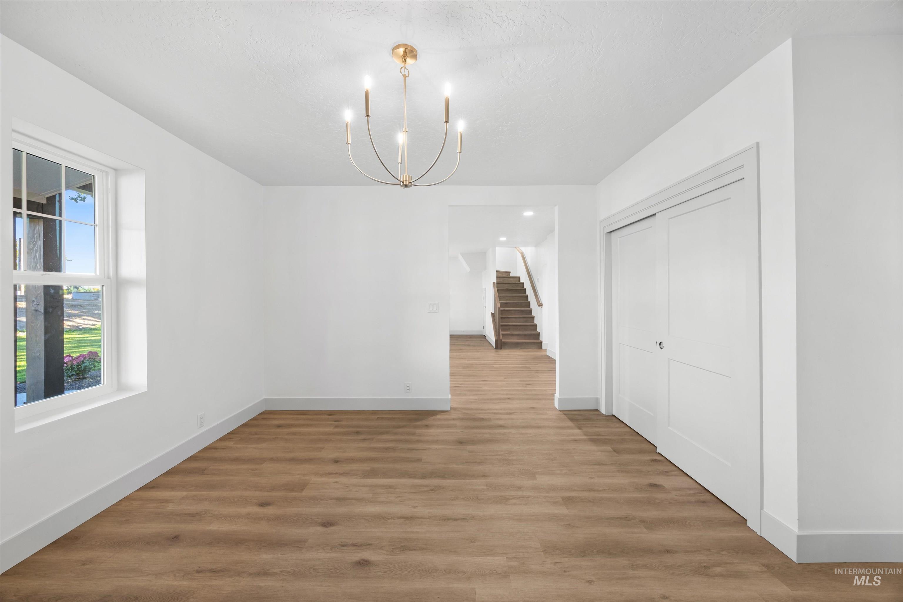 Unfurnished dining area with stairway, light wood-type flooring, and a chandelier