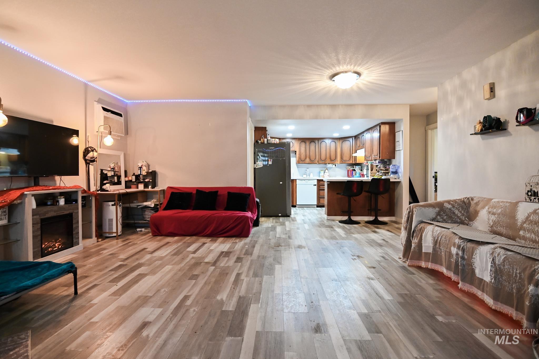 Living room with light wood-style floors and a warm lit fireplace