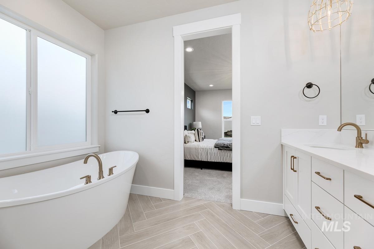 Full bath featuring a freestanding tub, vanity, connected bathroom, and recessed lighting