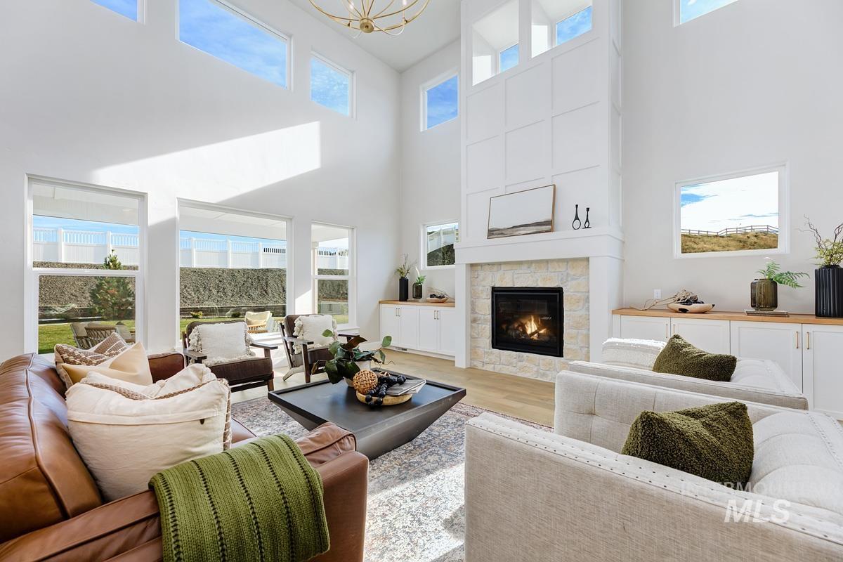 Living area with light wood-type flooring, a fireplace, and a towering ceiling