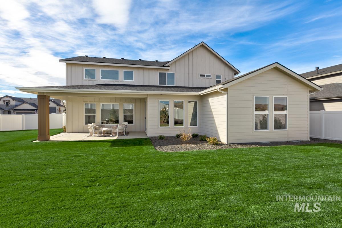 Rear view of property featuring board and batten siding, a patio, and a shingled roof