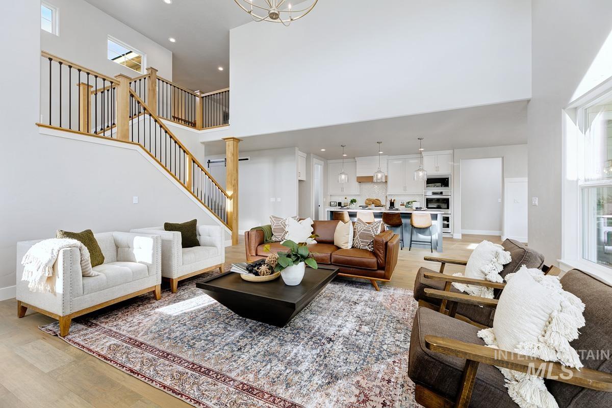 Living area featuring light wood-type flooring, recessed lighting, stairway, a high ceiling, and a chandelier