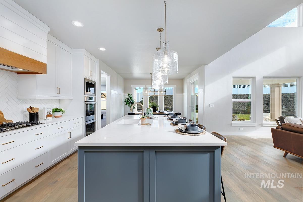 Kitchen with white cabinetry, tasteful backsplash, hanging light fixtures, light wood-type flooring, and recessed lighting