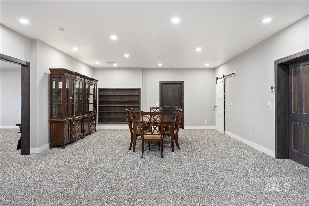Dining room with a barn door, recessed lighting, and light colored carpet