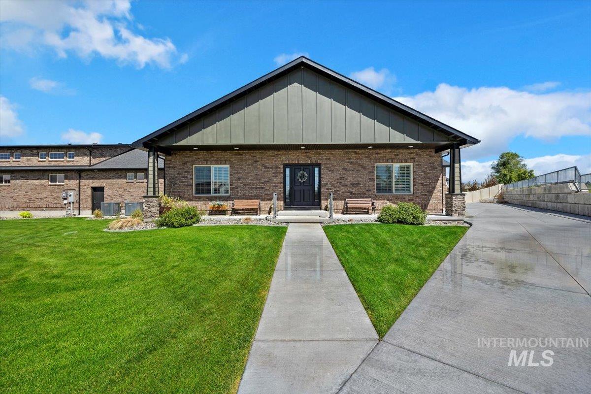 View of front facade with covered porch, board and batten siding, and brick siding