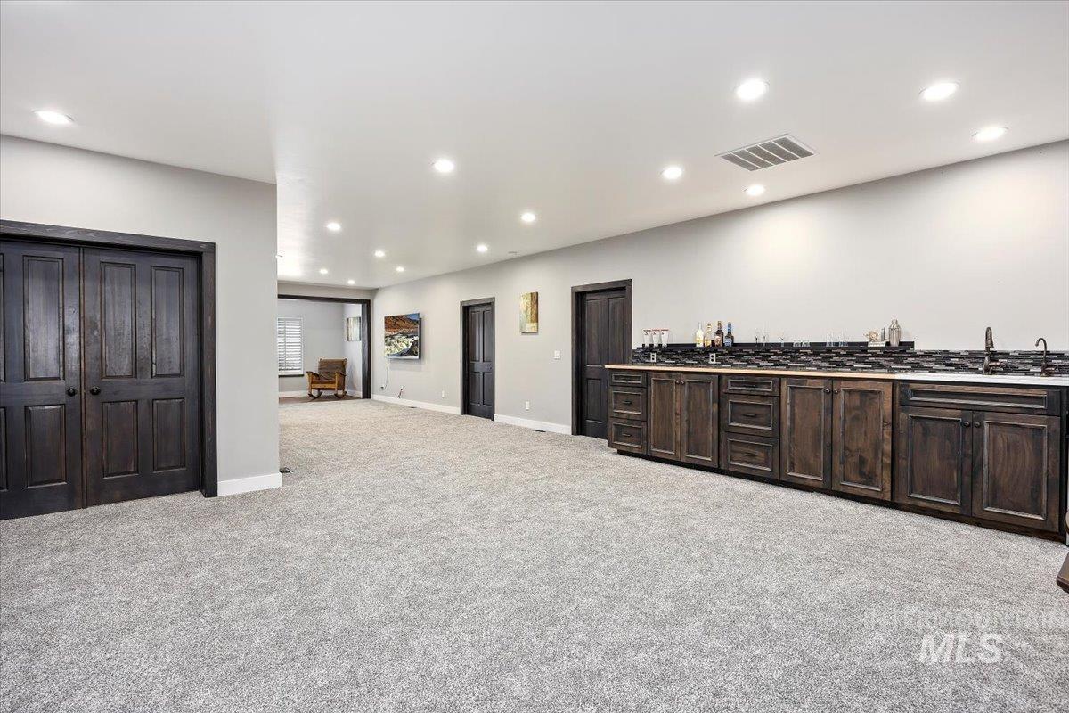 Kitchen featuring dark brown cabinetry, light colored carpet, recessed lighting, and dark countertops