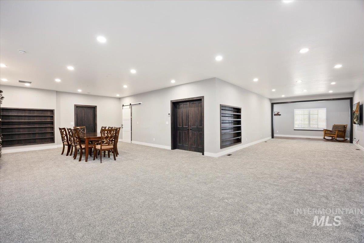 Dining space with a barn door, recessed lighting, and light carpet