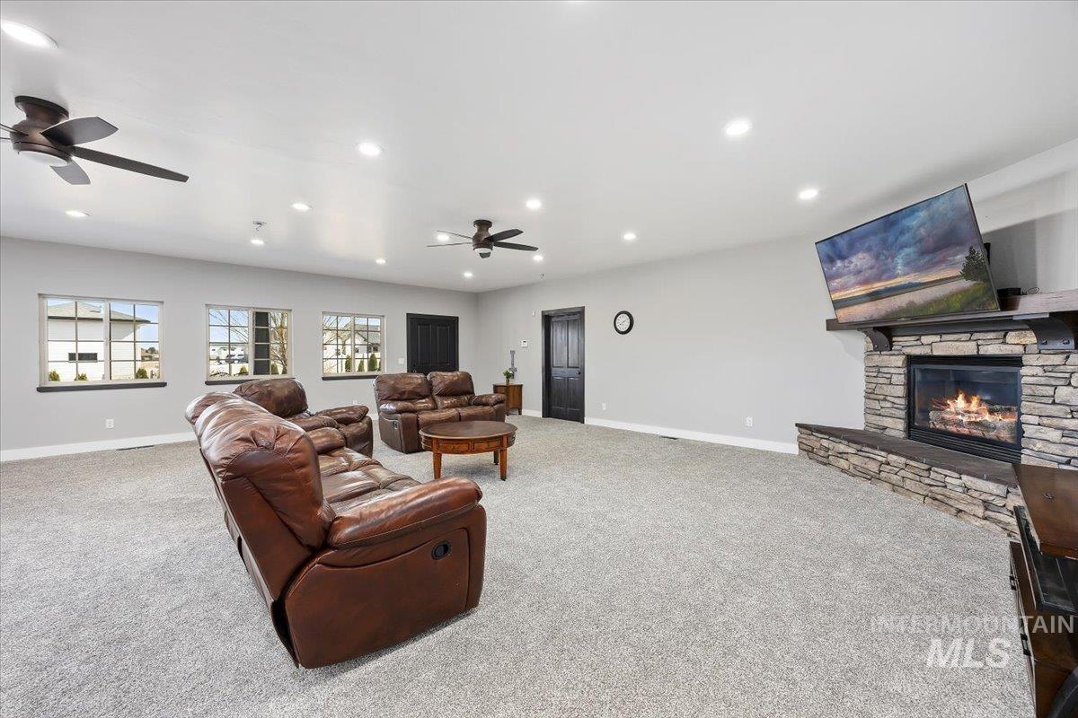 Living room with light colored carpet, recessed lighting, a fireplace, and a ceiling fan