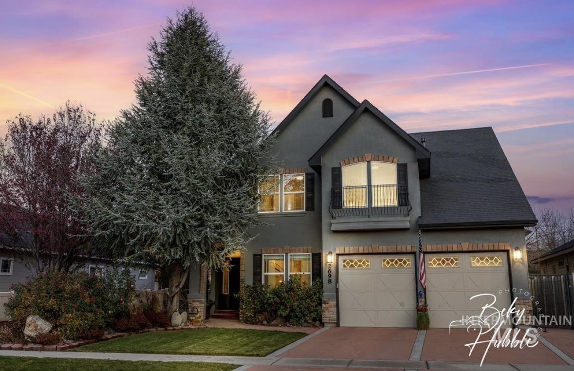 Traditional-style house featuring a balcony, stucco siding, a garage, and concrete driveway