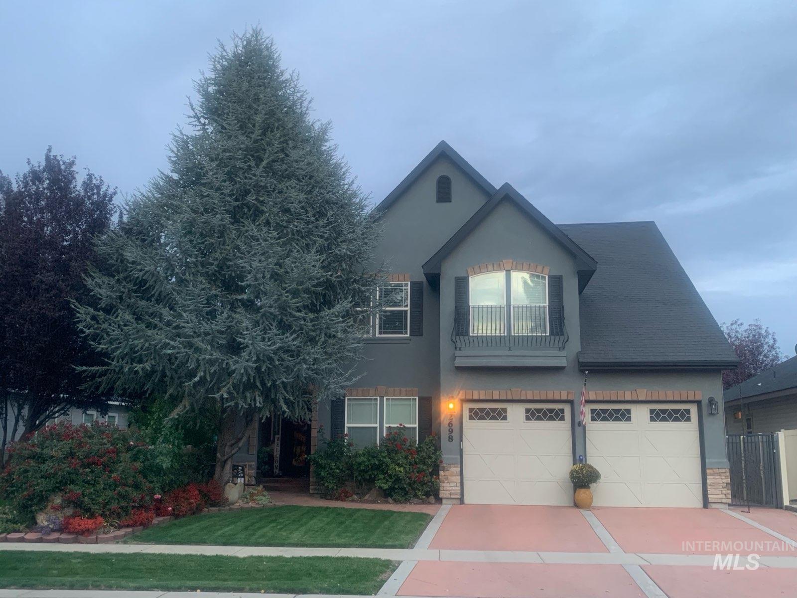 Traditional home with a balcony, stucco siding, driveway, and stone siding