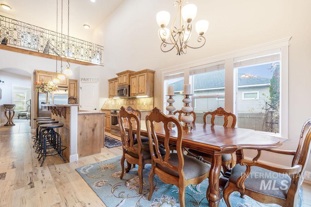 Dining space with arched walkways, a high ceiling, light wood finished floors, and a chandelier