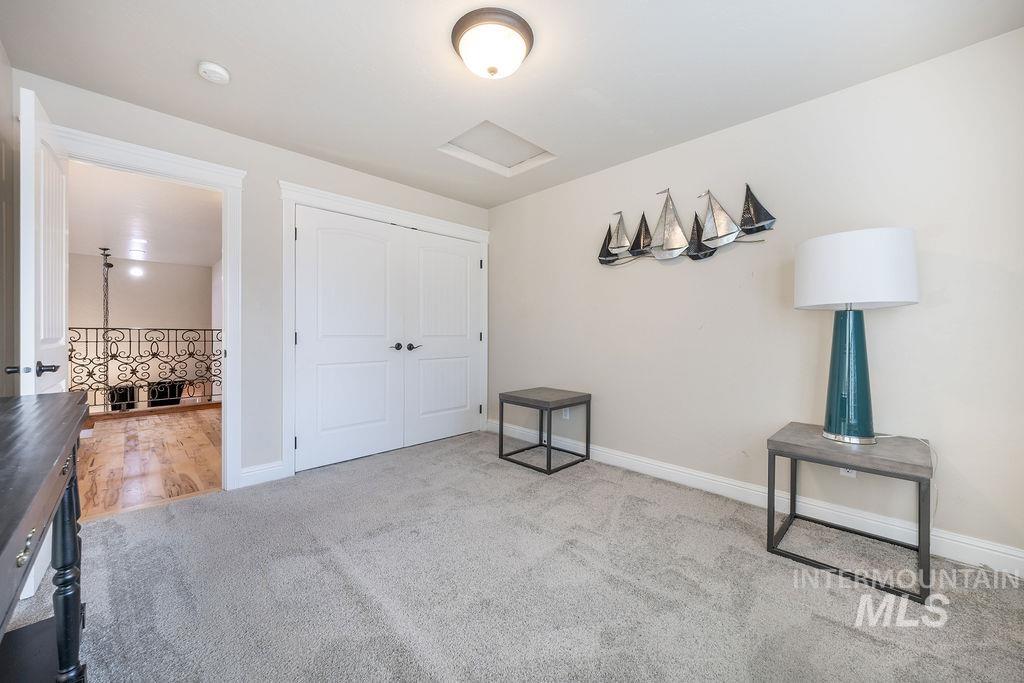 Unfurnished bedroom featuring attic access, light colored carpet, and a closet