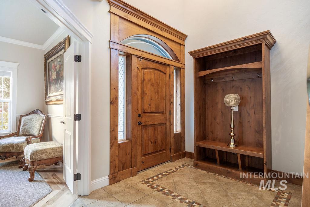 Foyer with inlaid floor details, tile patterned flooring, plenty of natural light, and crown molding