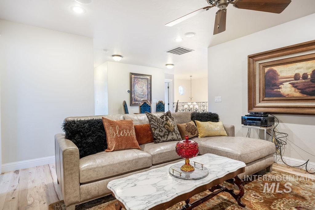 Living room featuring a ceiling fan, light wood-type flooring, and a chandelier