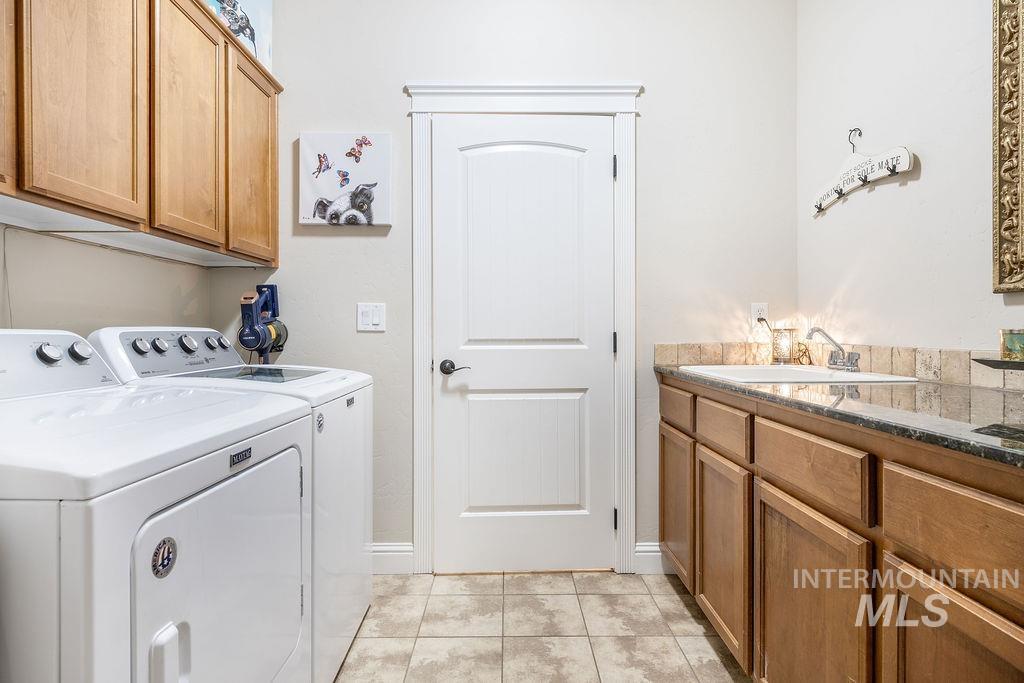 Washroom featuring cabinet space, independent washer and dryer, and light tile patterned flooring