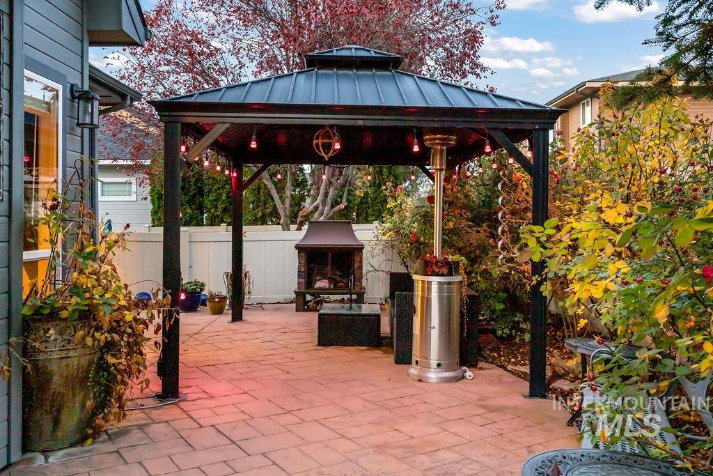 View of patio with a gazebo and an outdoor stone fireplace