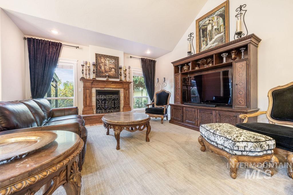Living area with a fireplace with raised hearth, healthy amount of natural light, high vaulted ceiling, and recessed lighting