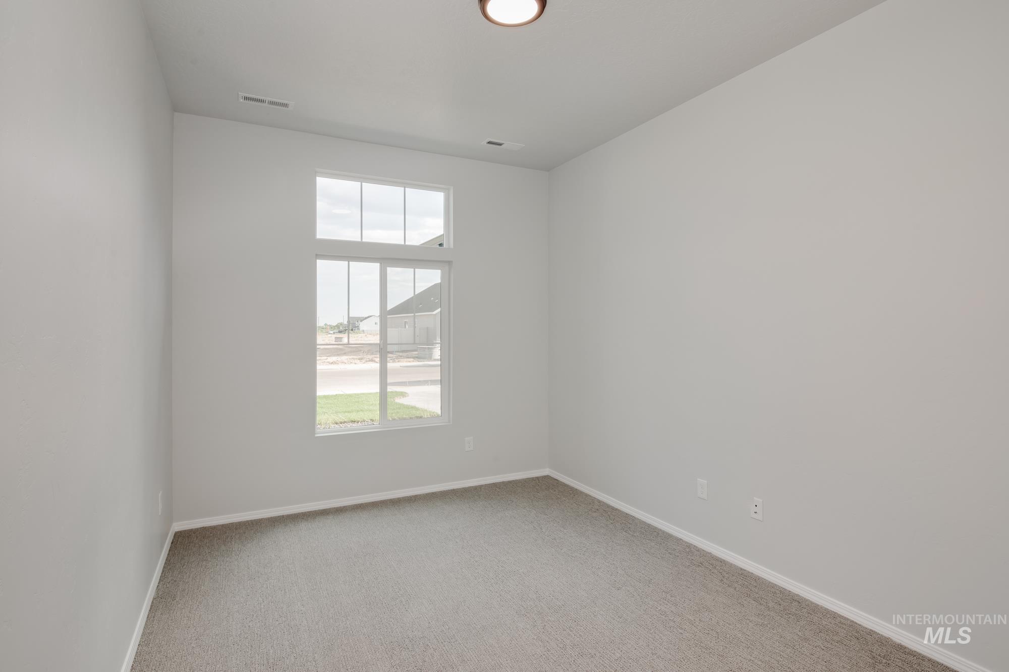 Spare room featuring light carpet and baseboards