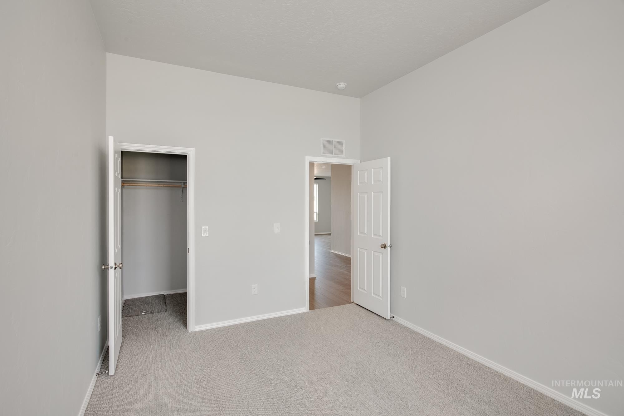 Unfurnished bedroom with a spacious closet and light colored carpet