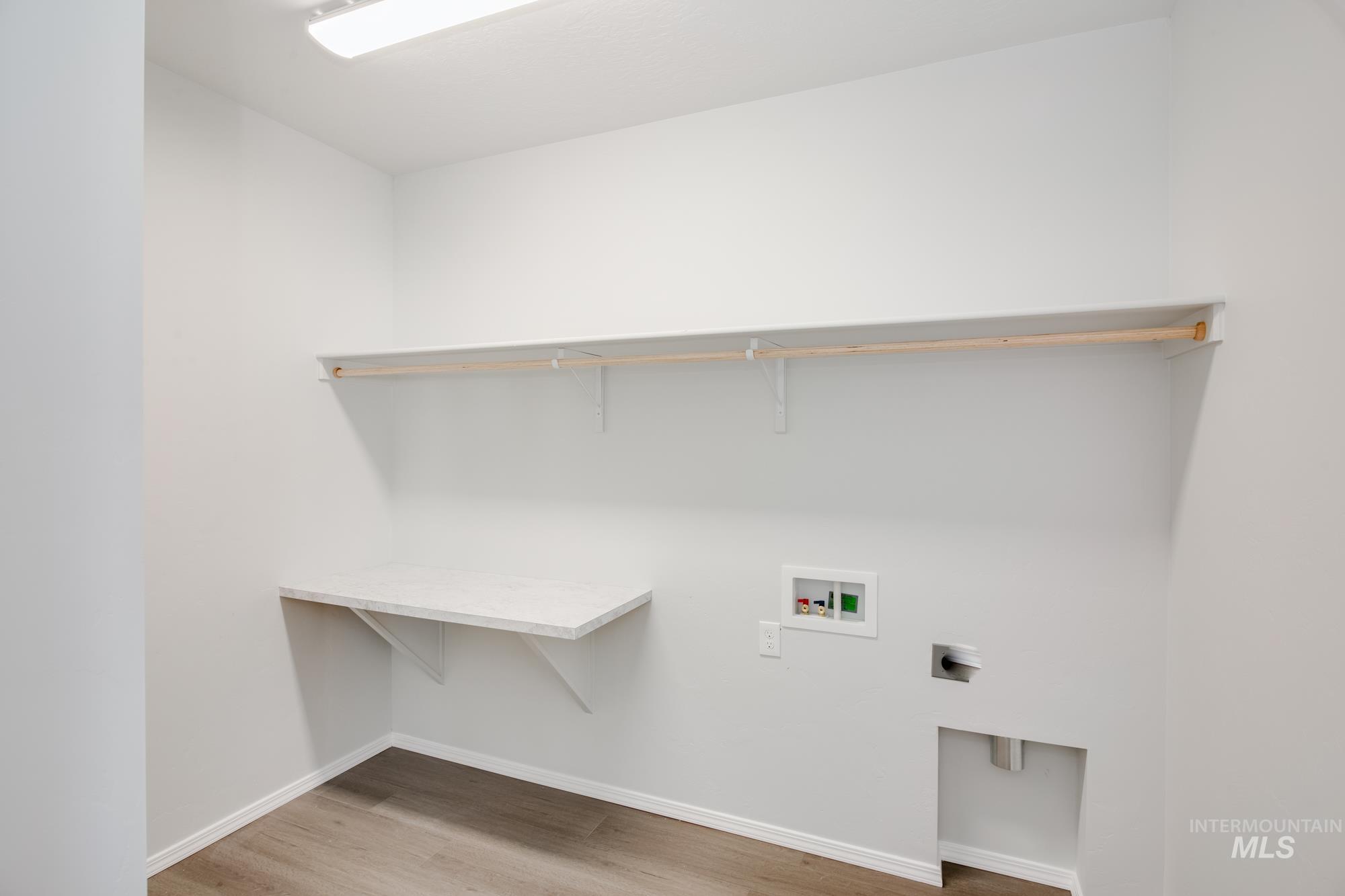 Washroom with light wood-style floors, hookup for a washing machine, and hookup for an electric dryer
