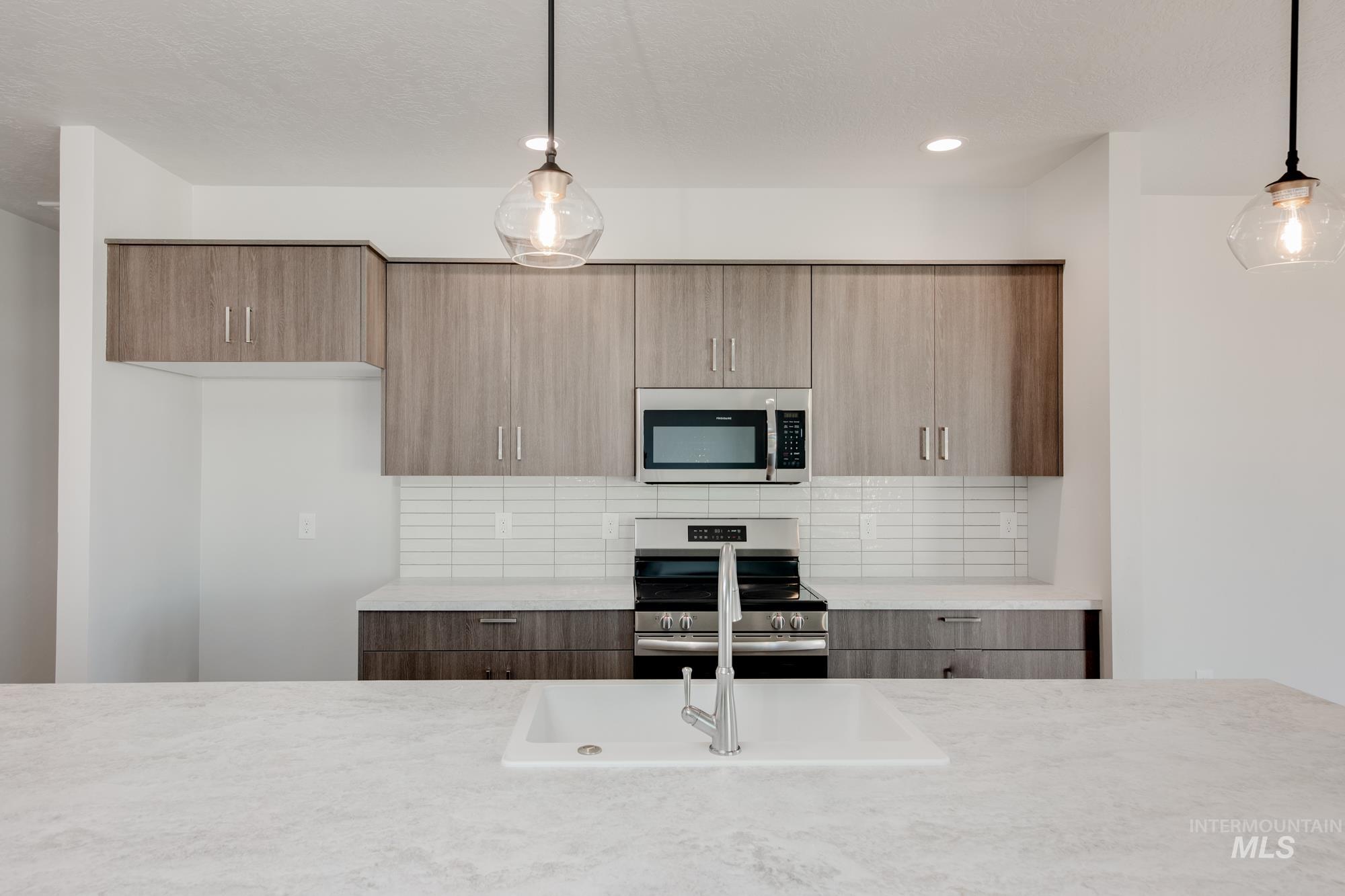 Kitchen with modern cabinets, appliances with stainless steel finishes, backsplash, pendant lighting, and recessed lighting