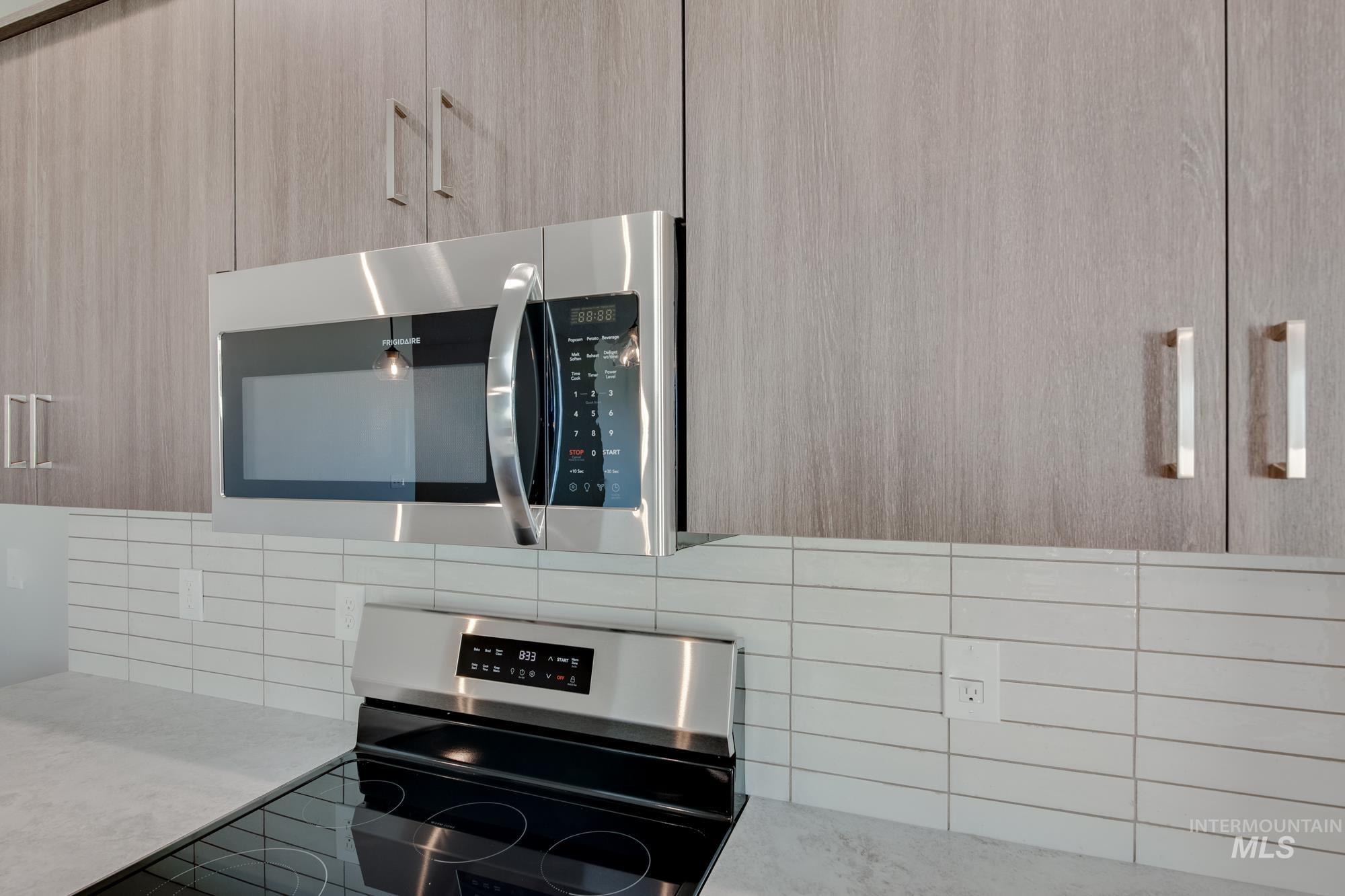 Kitchen view of modern cabinets, appliances with stainless steel finishes, light brown cabinetry, and decorative backsplash