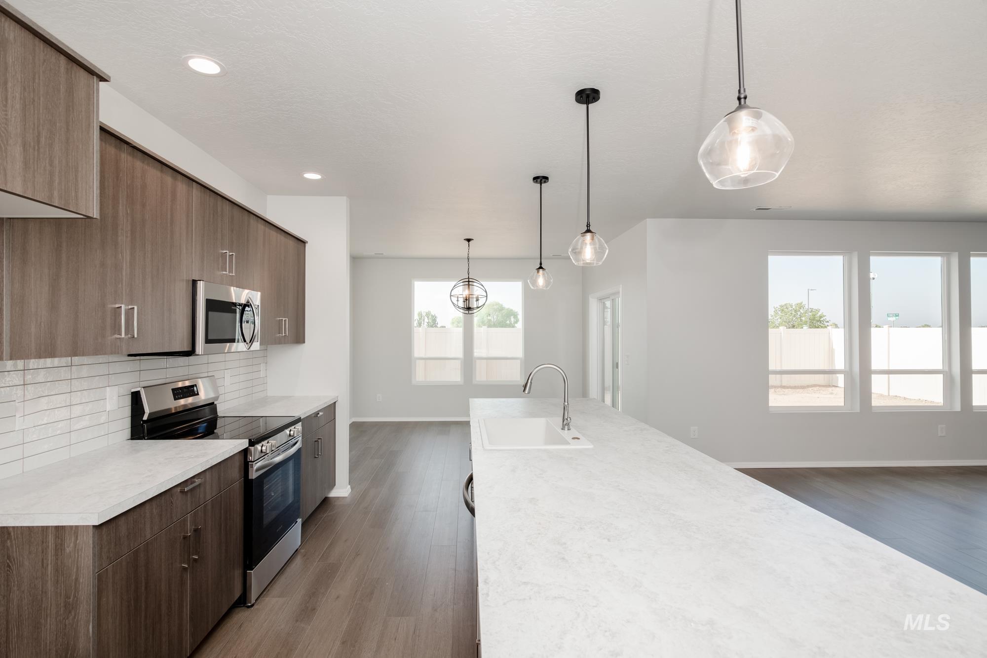 Kitchen featuring stainless steel appliances, pendant lighting, dark wood-style floors, decorative backsplash, and modern cabinets