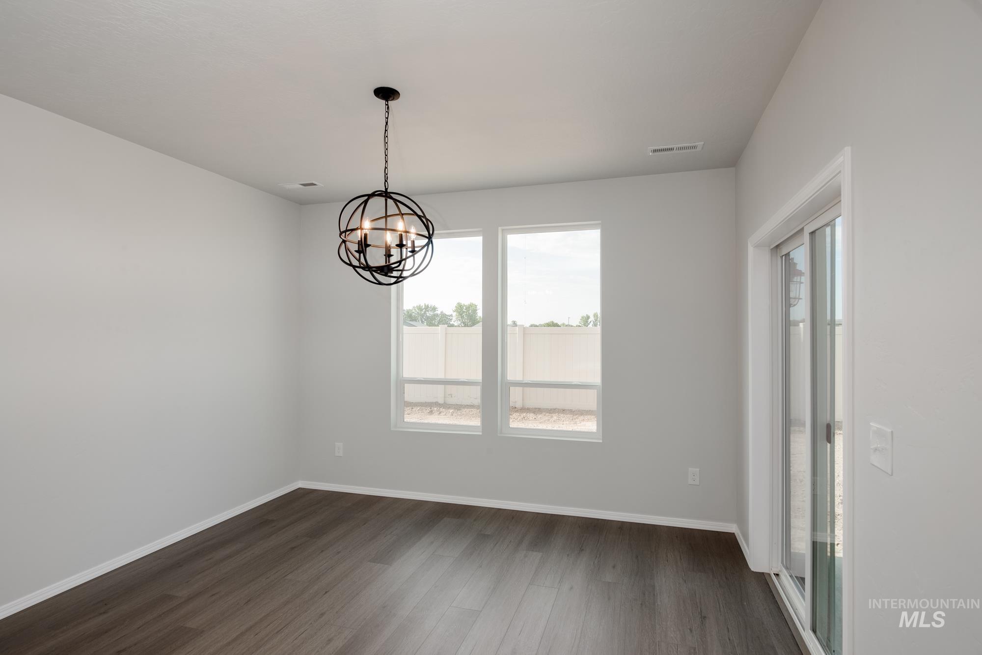Spare room with dark wood-style flooring and a chandelier