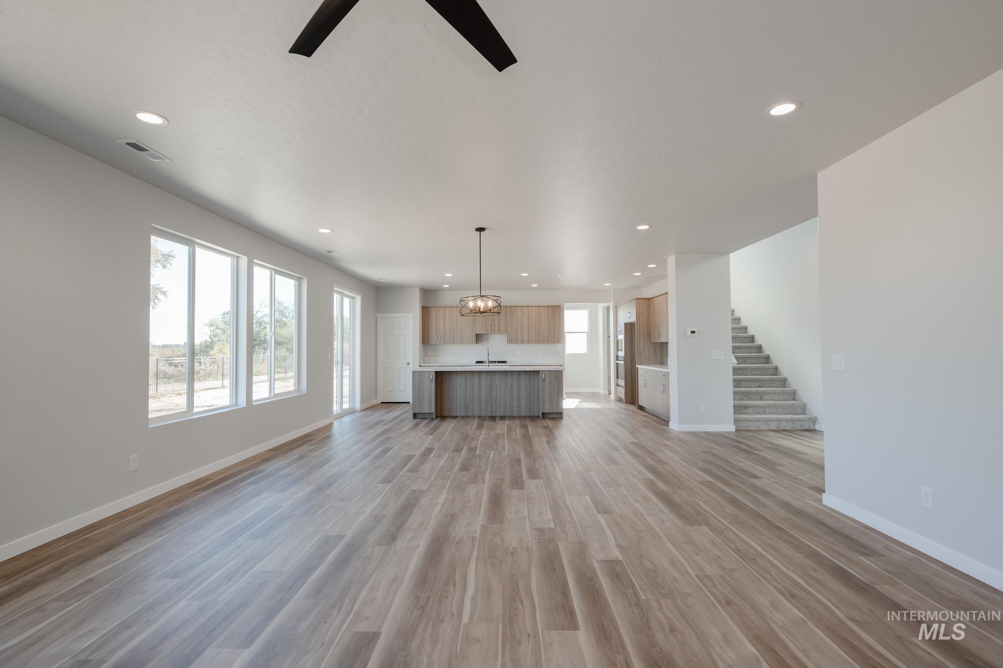 Unfurnished living room with light wood finished floors, recessed lighting, stairway, and a ceiling fan