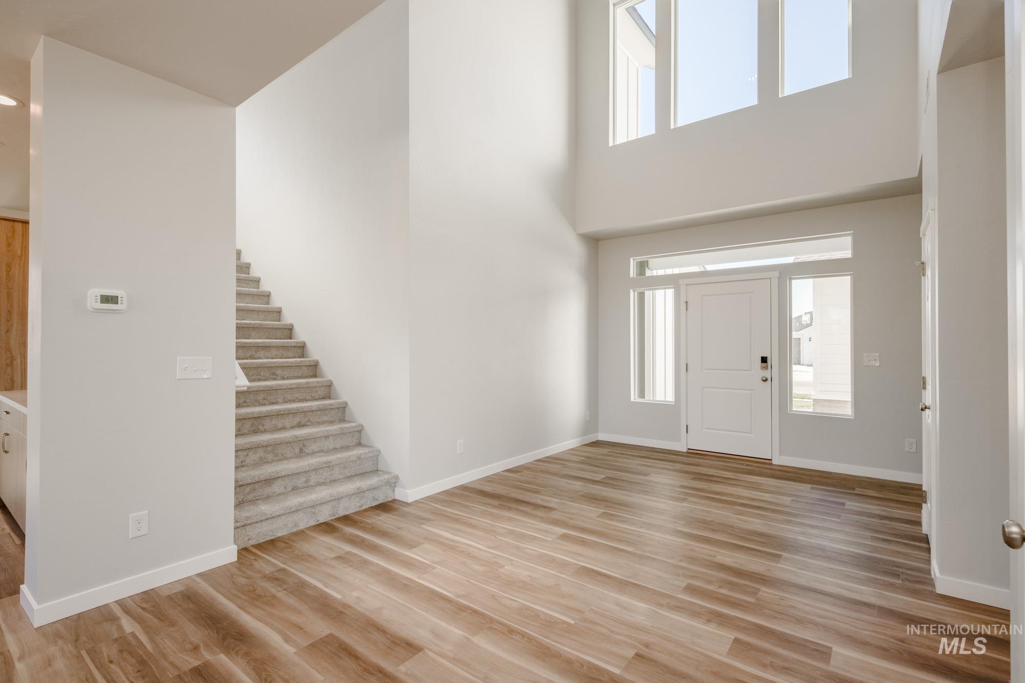 Entrance foyer with light wood-style flooring, stairway, and a towering ceiling