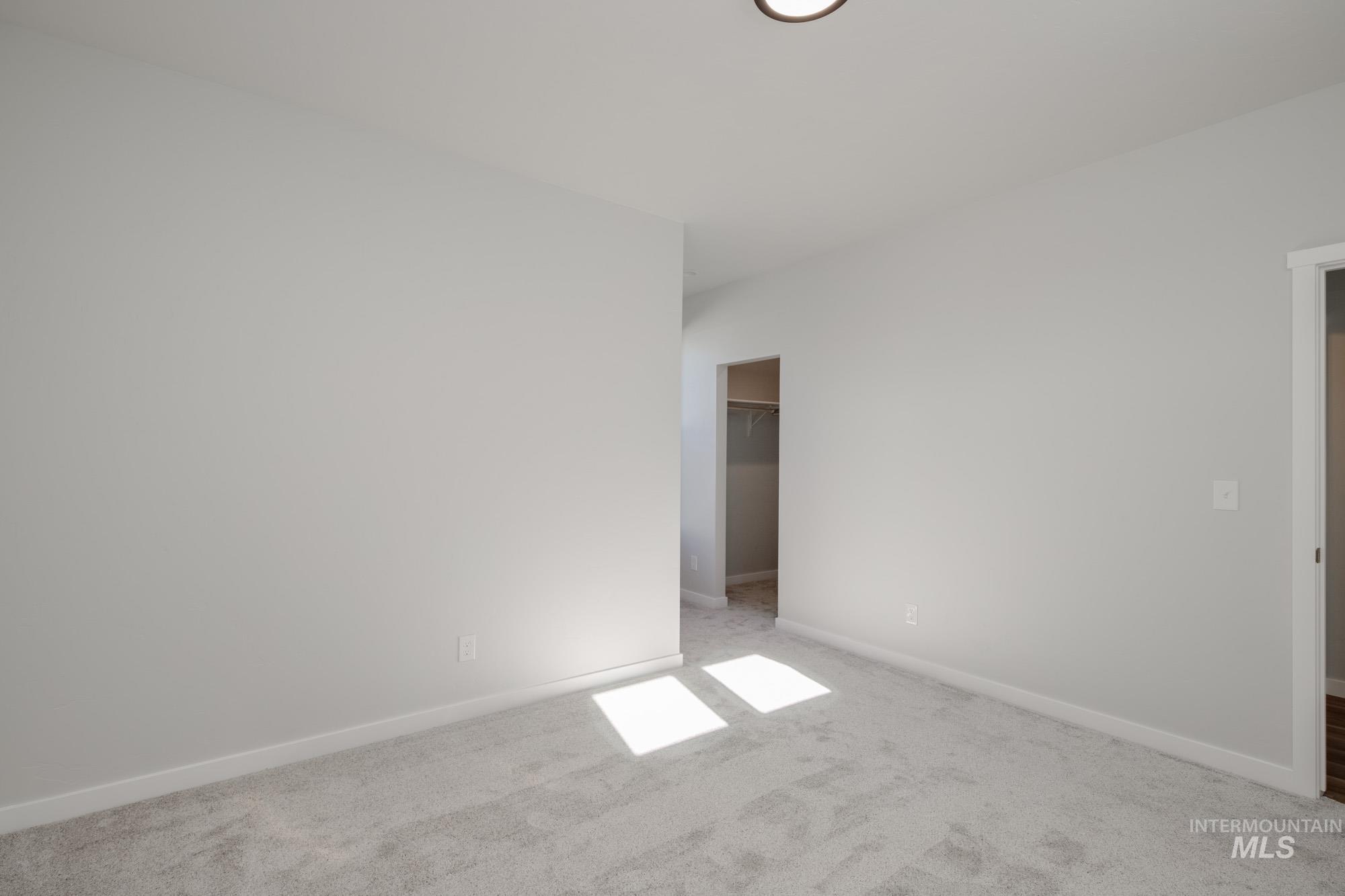 Carpeted spare room featuring baseboards
