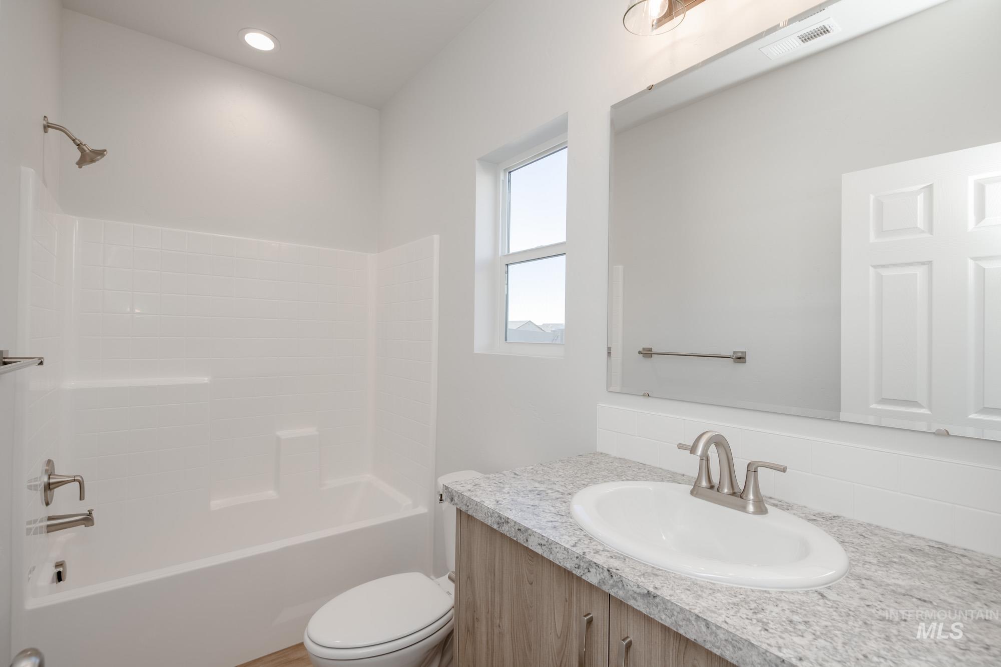 Bathroom with washtub / shower combination, vanity, and recessed lighting