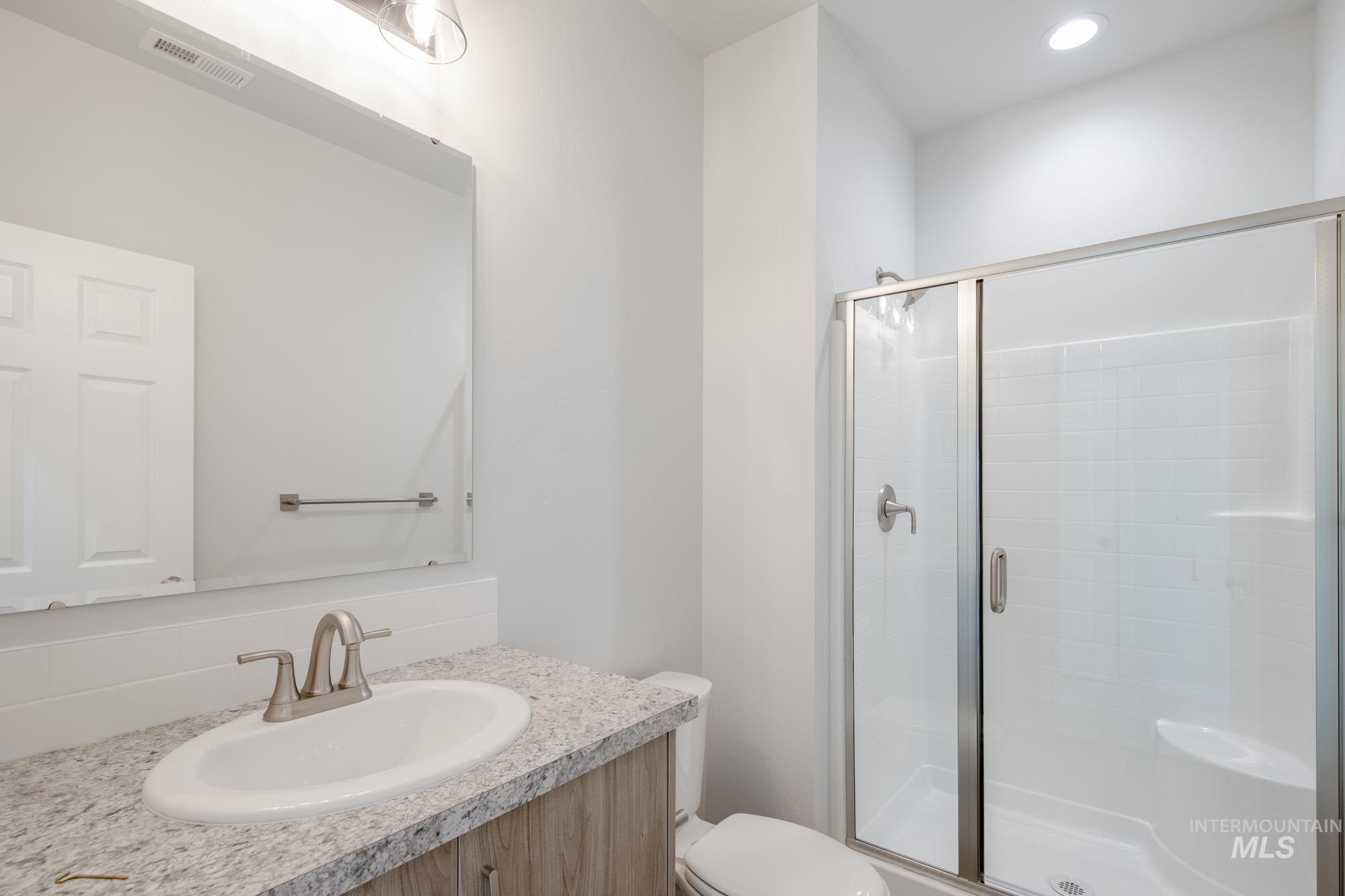 Bathroom featuring a stall shower, vanity, and recessed lighting