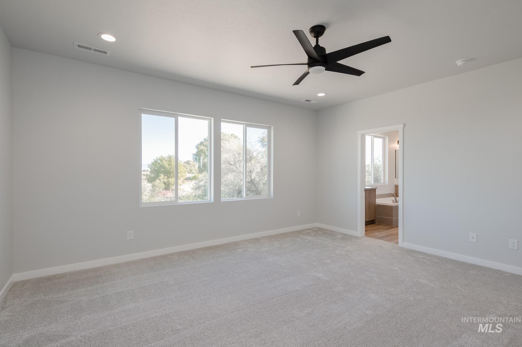 Unfurnished bedroom with multiple windows, light colored carpet, a ceiling fan, recessed lighting, and connected bathroom