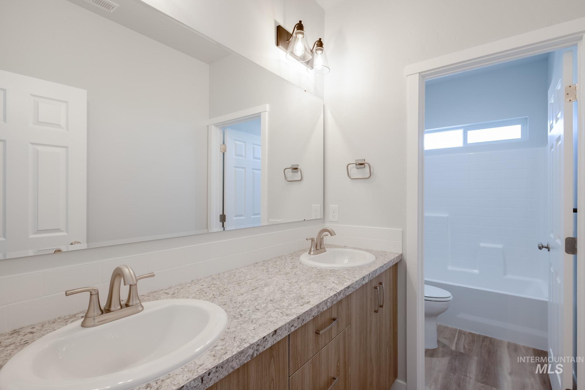 Bathroom featuring double vanity, light wood-style floors, and  shower combination