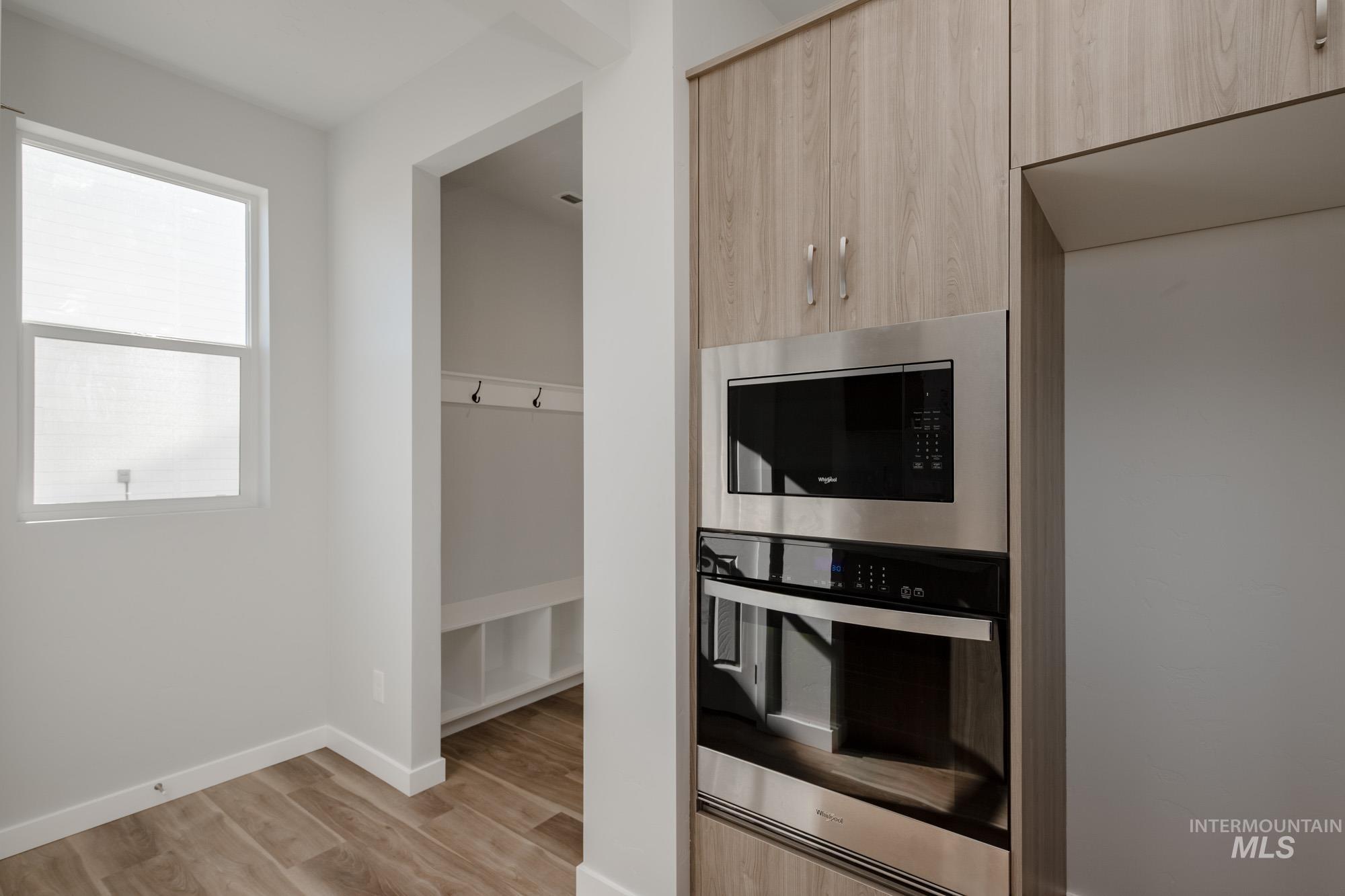 Kitchen with appliances with stainless steel finishes, light brown cabinets, modern cabinets, and light wood-type flooring