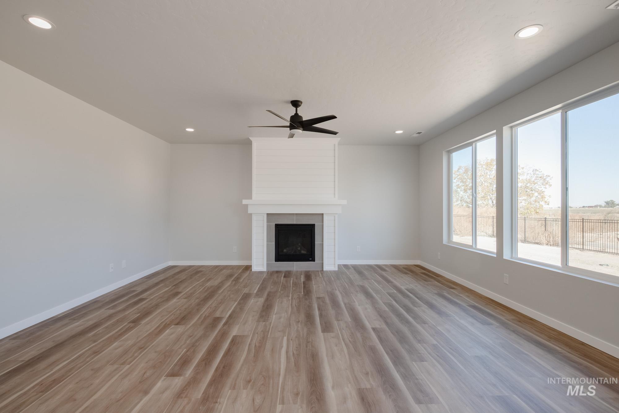 Unfurnished living room featuring recessed lighting, light wood-style flooring, a ceiling fan, and a fireplace