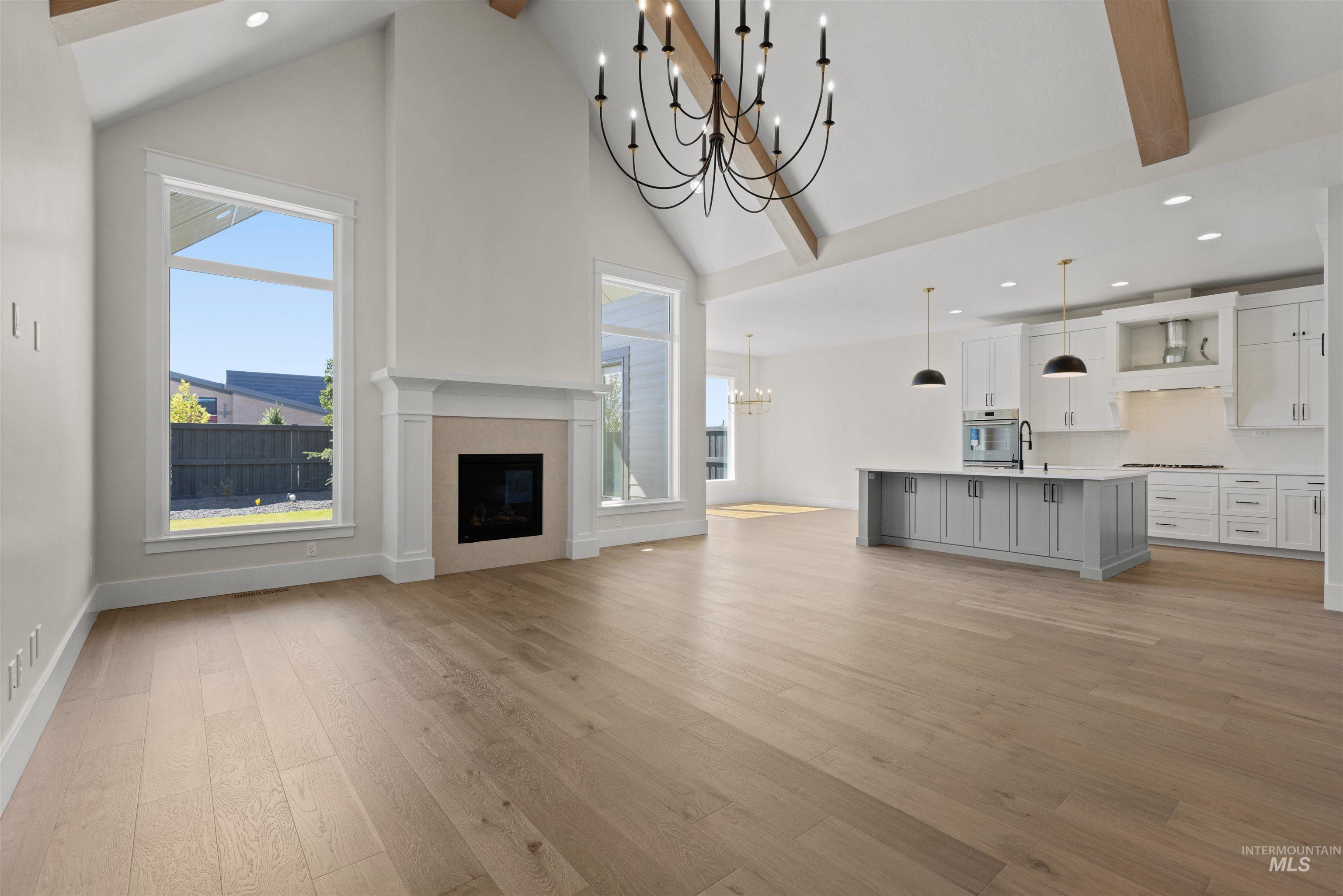 Unfurnished living room with a chandelier, high vaulted ceiling, recessed lighting, light wood-style flooring, and beamed ceiling