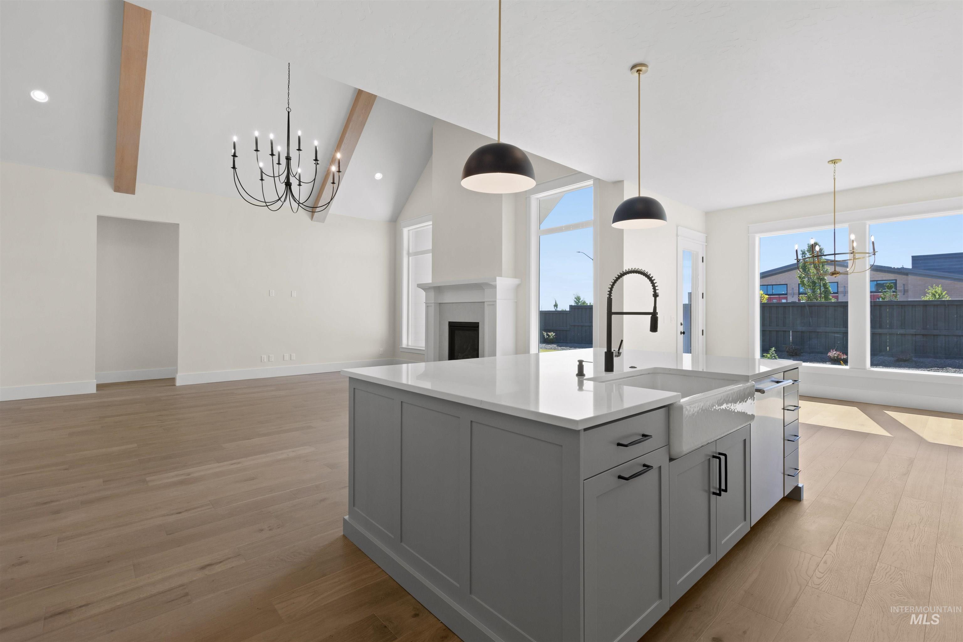 Kitchen featuring a chandelier, open floor plan, light wood-type flooring, a kitchen island with sink, and high vaulted ceiling