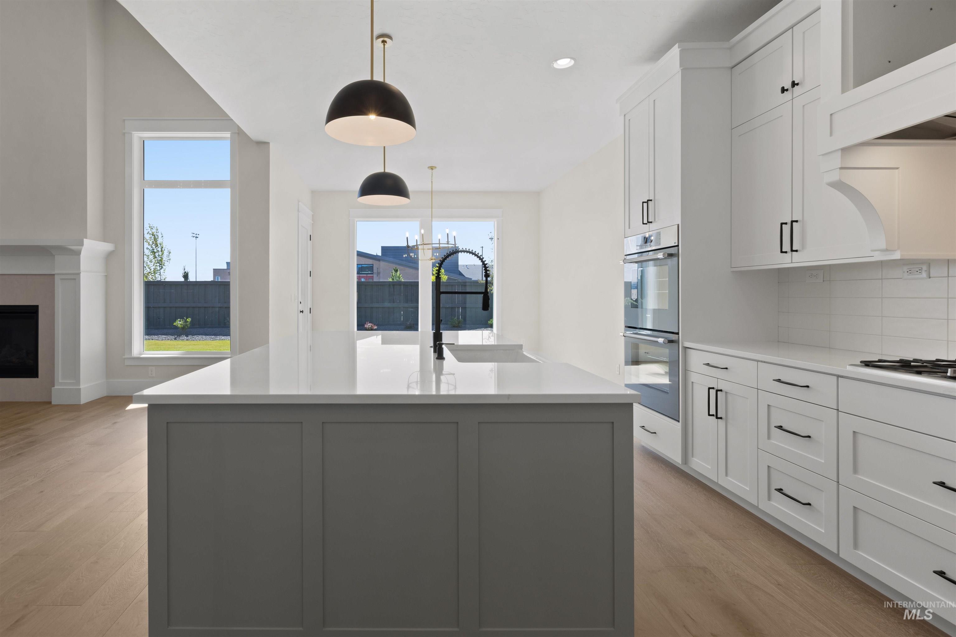 Kitchen with healthy amount of natural light, light wood finished floors, double oven, and light countertops