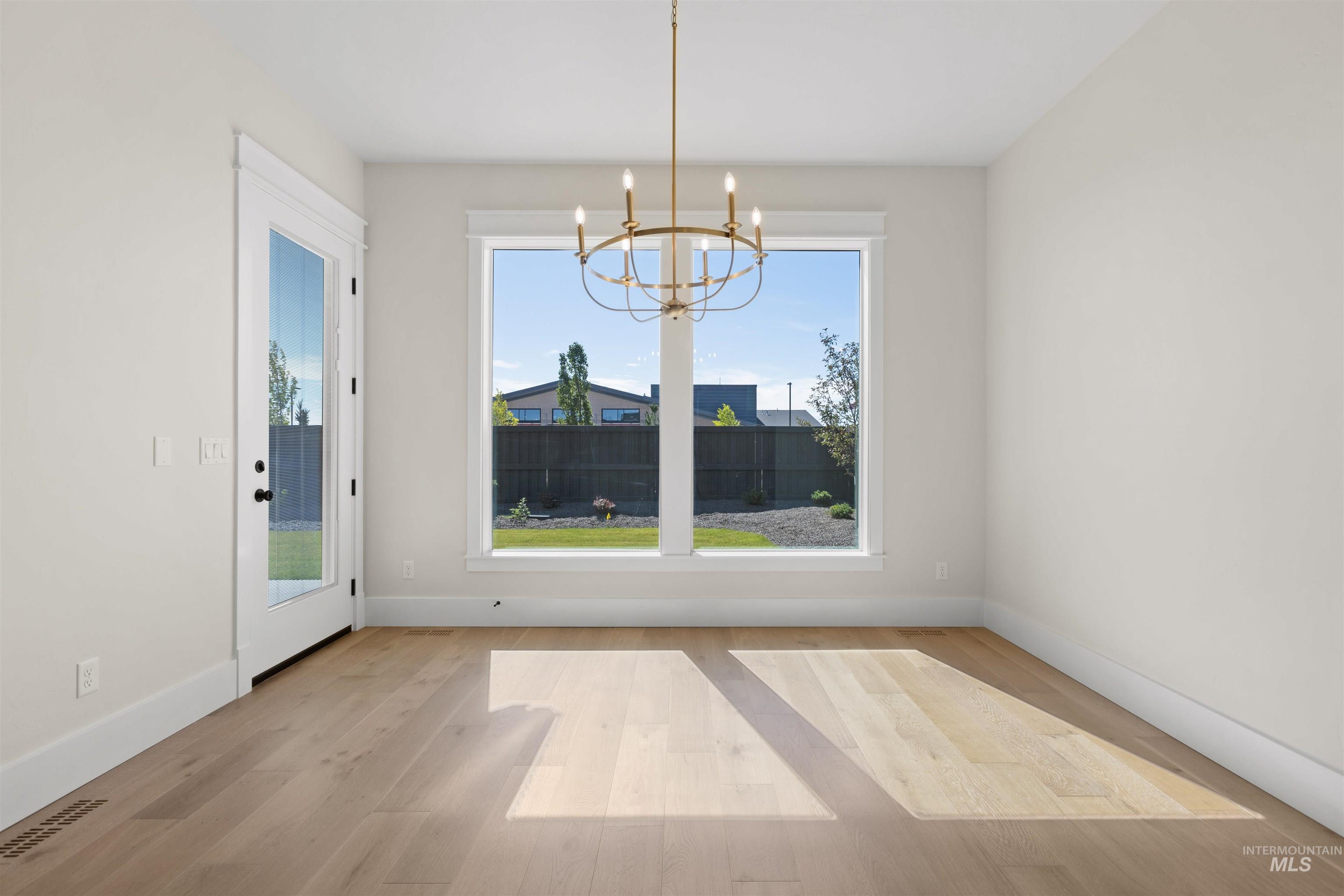 Unfurnished dining area featuring a chandelier and wood finished floors