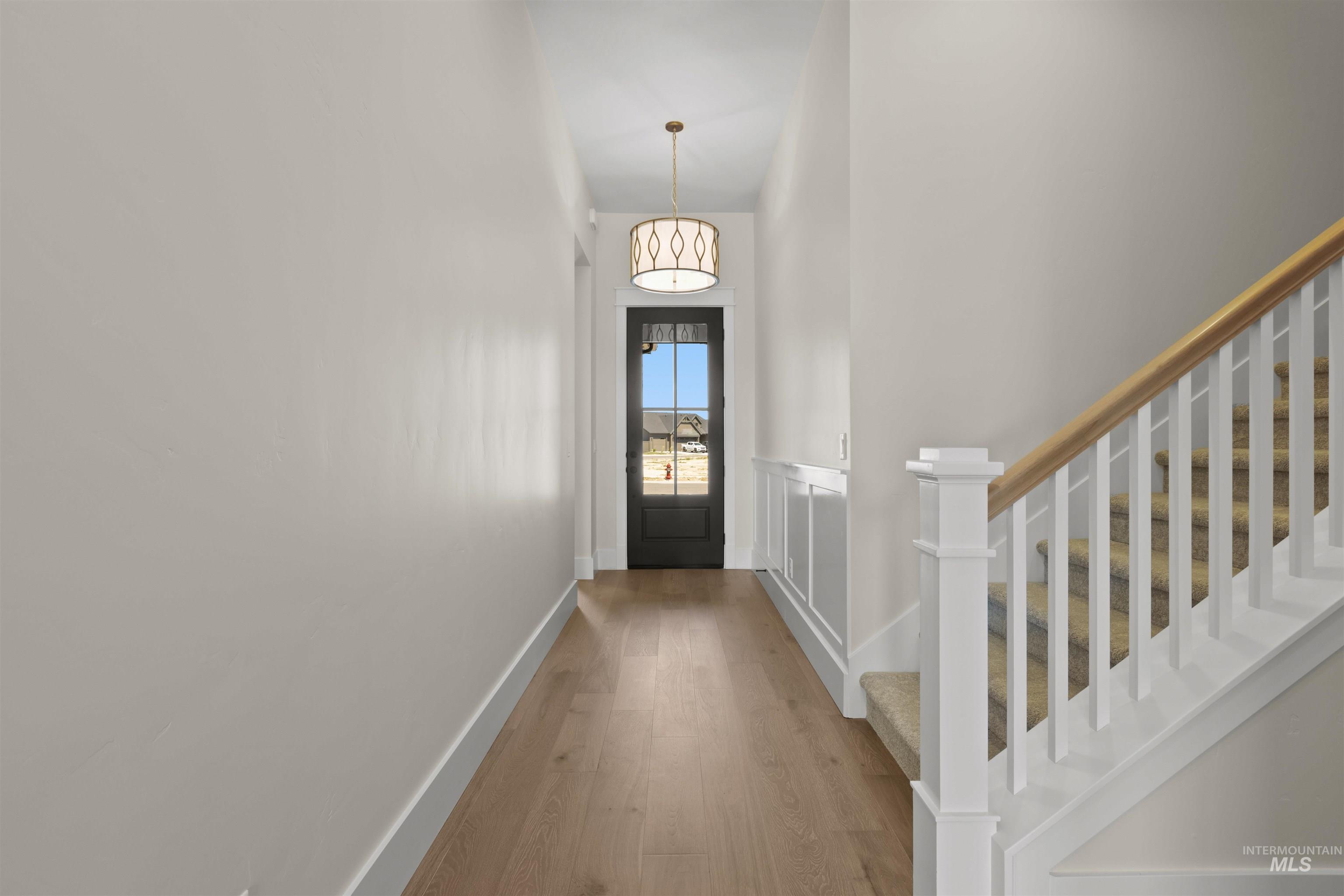 Entryway with stairway, wood finished floors, and a high ceiling
