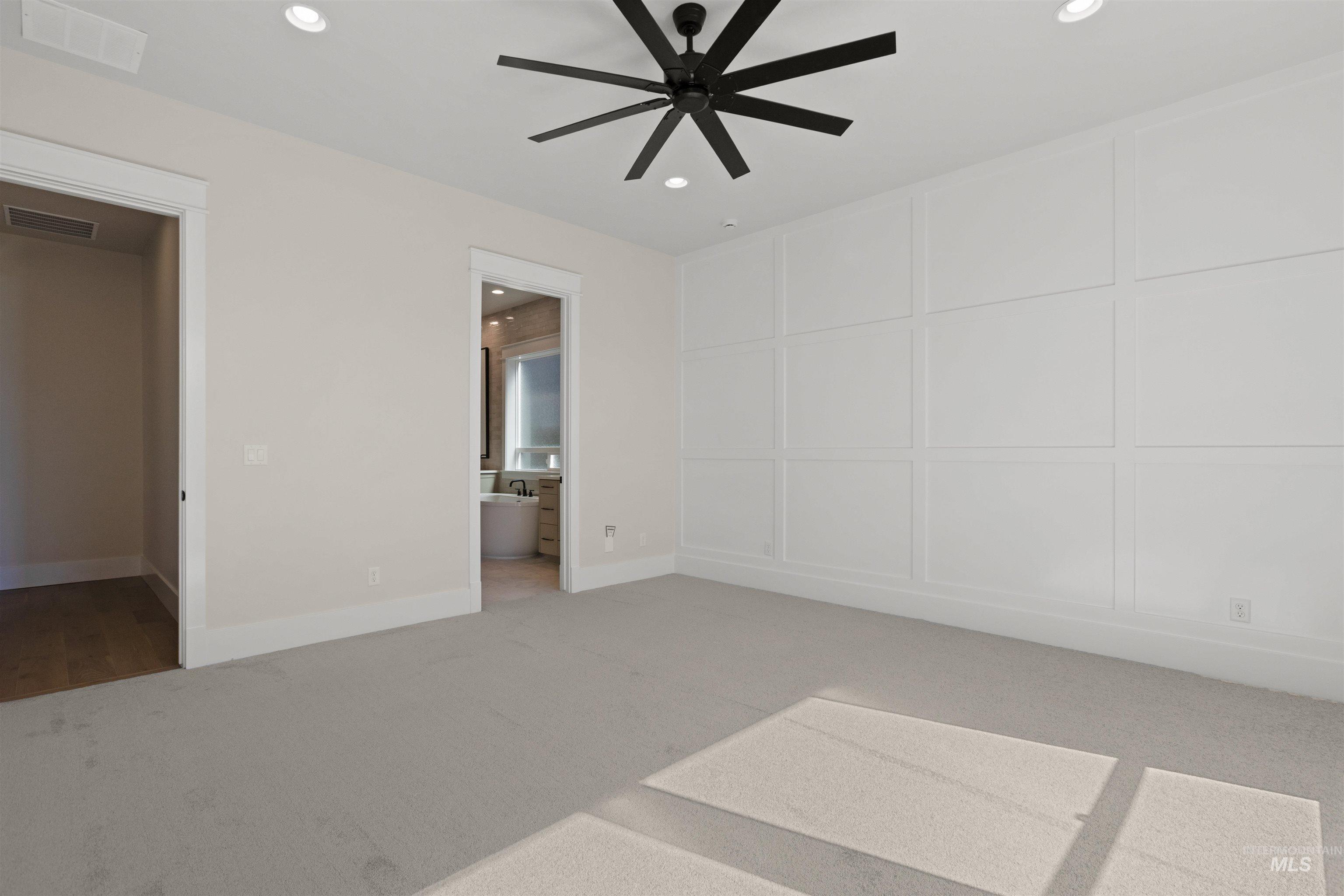 Unfurnished bedroom featuring recessed lighting, carpet, a decorative wall, and ensuite bathroom