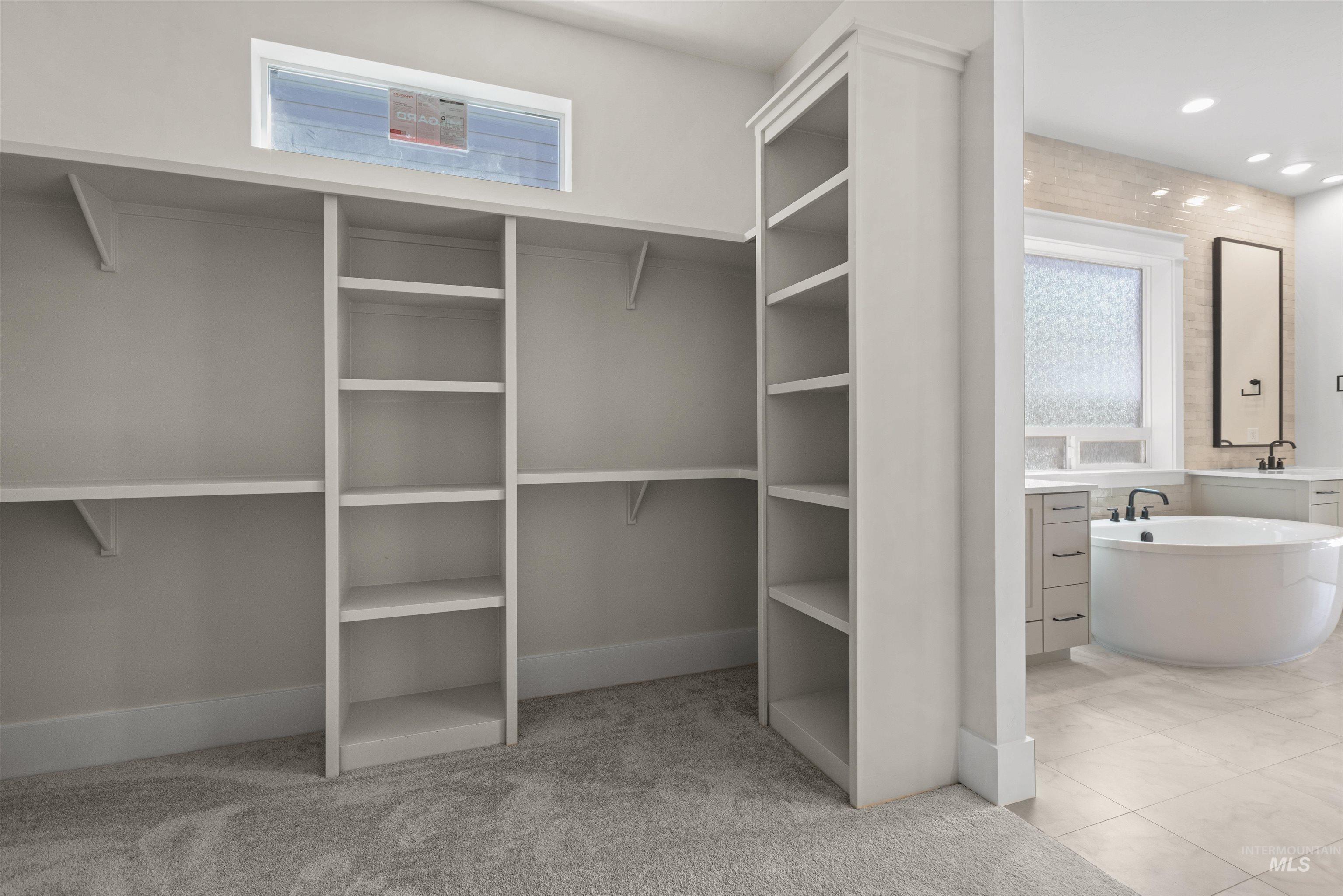 Walk in closet featuring light colored carpet