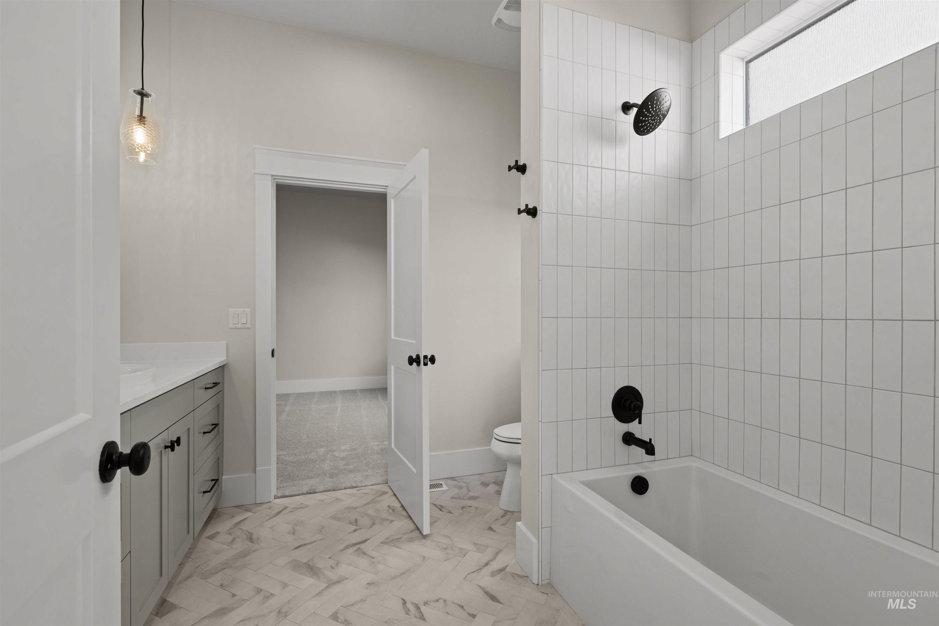 Bathroom with marble finish floors, vanity, and washtub / shower combination