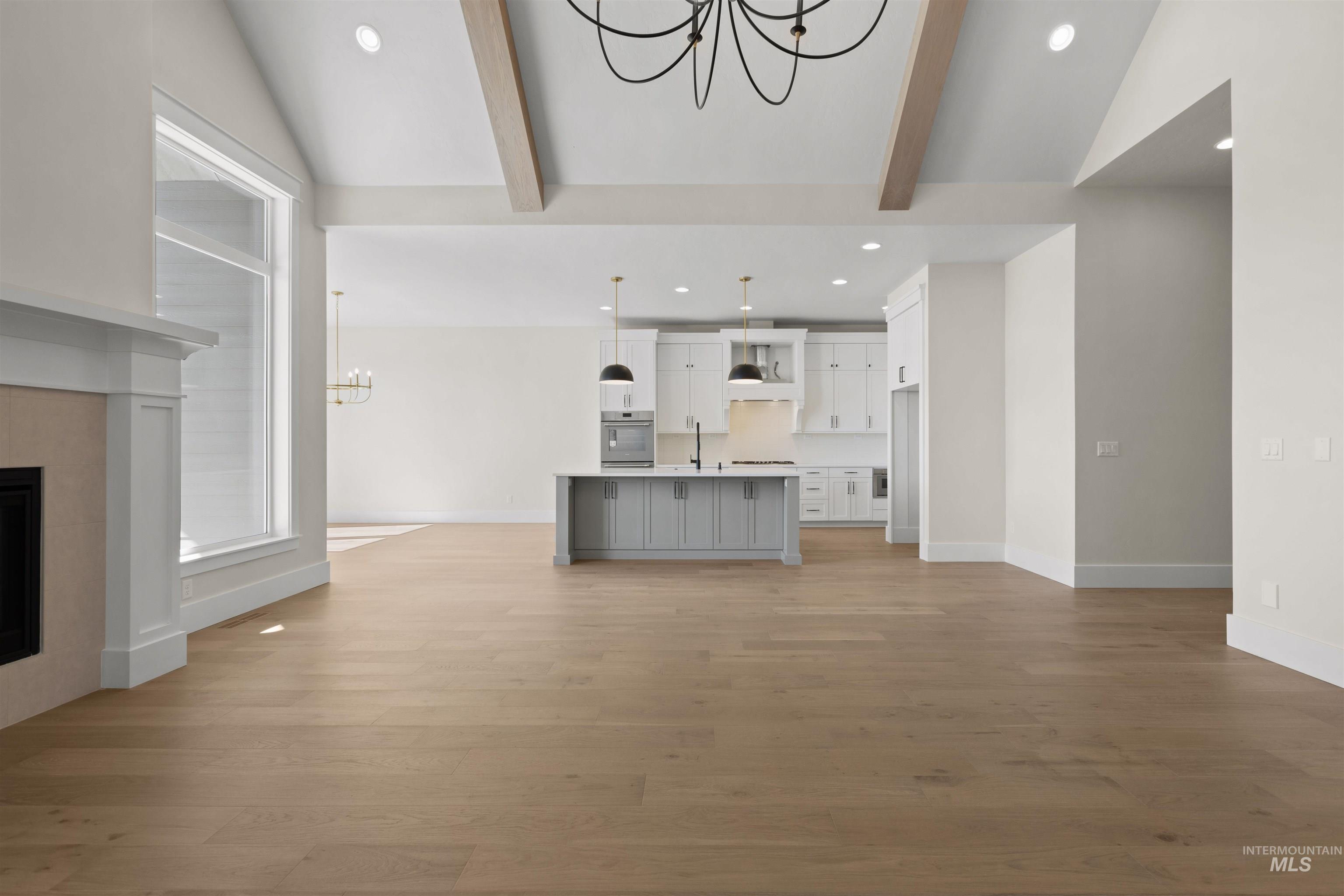 Unfurnished living room with a chandelier, recessed lighting, light wood finished floors, and a fireplace