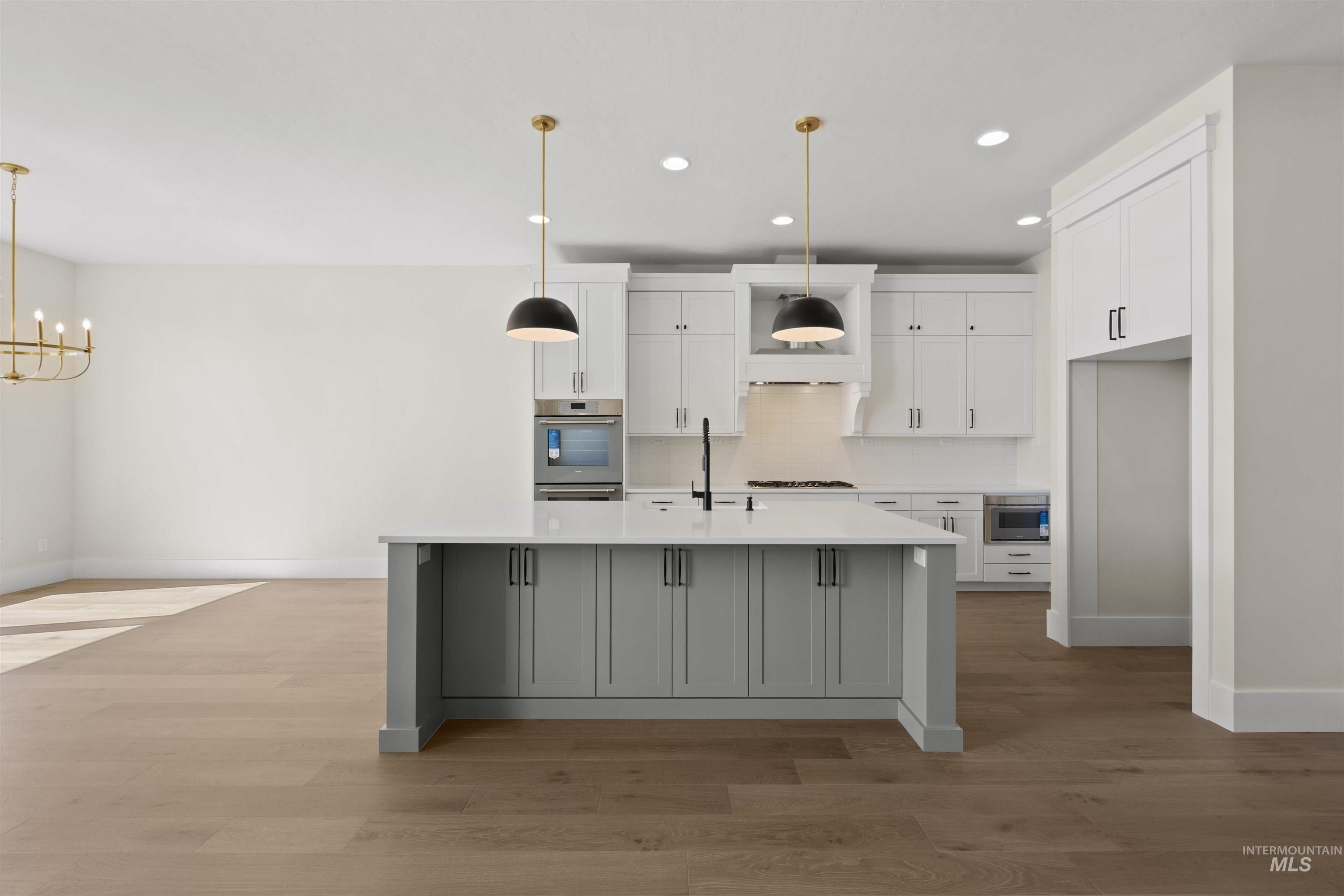 Kitchen featuring recessed lighting, white cabinets, light wood-type flooring, a chandelier, and light countertops