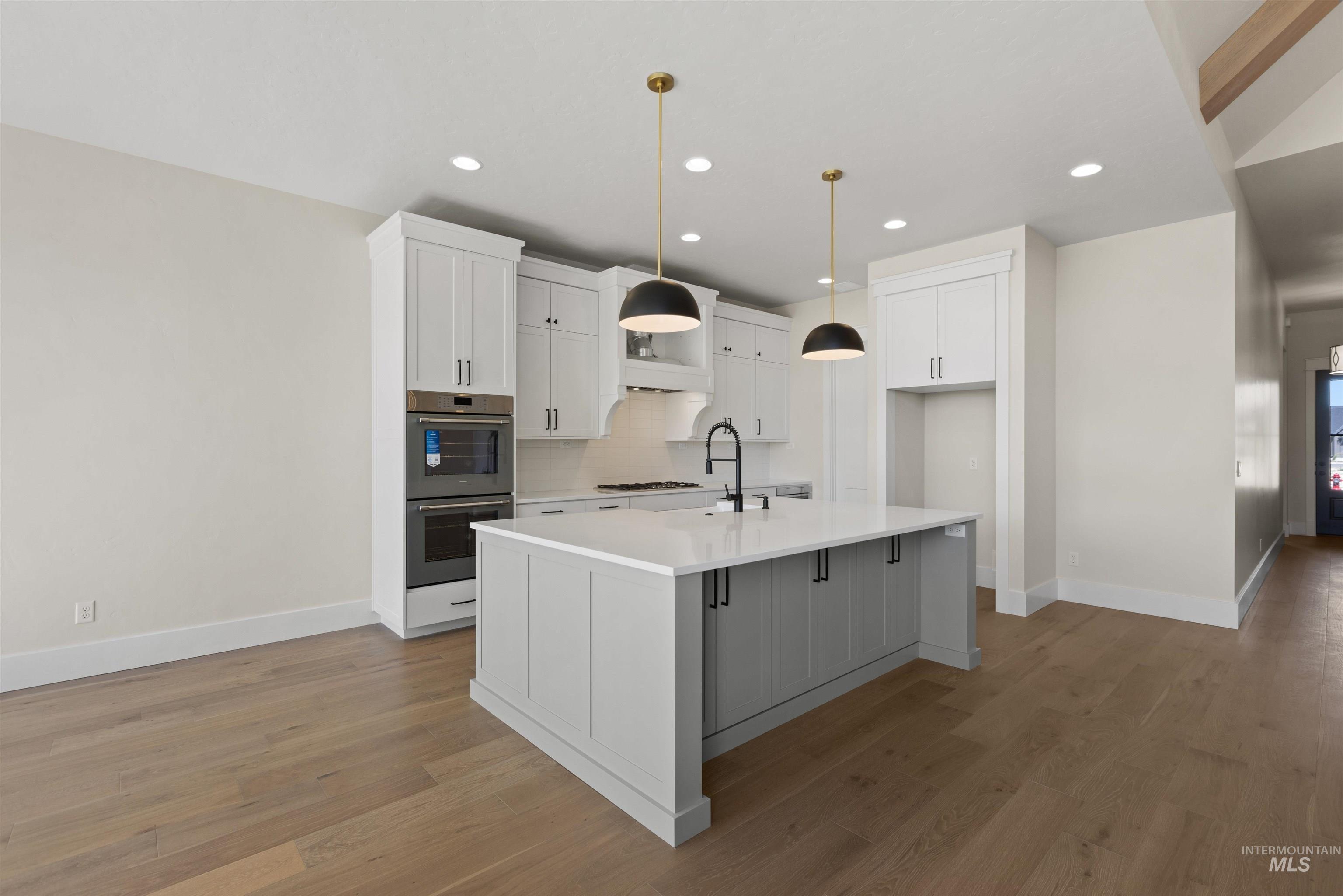 Kitchen featuring double oven, white cabinets, light countertops, light wood-type flooring, and recessed lighting