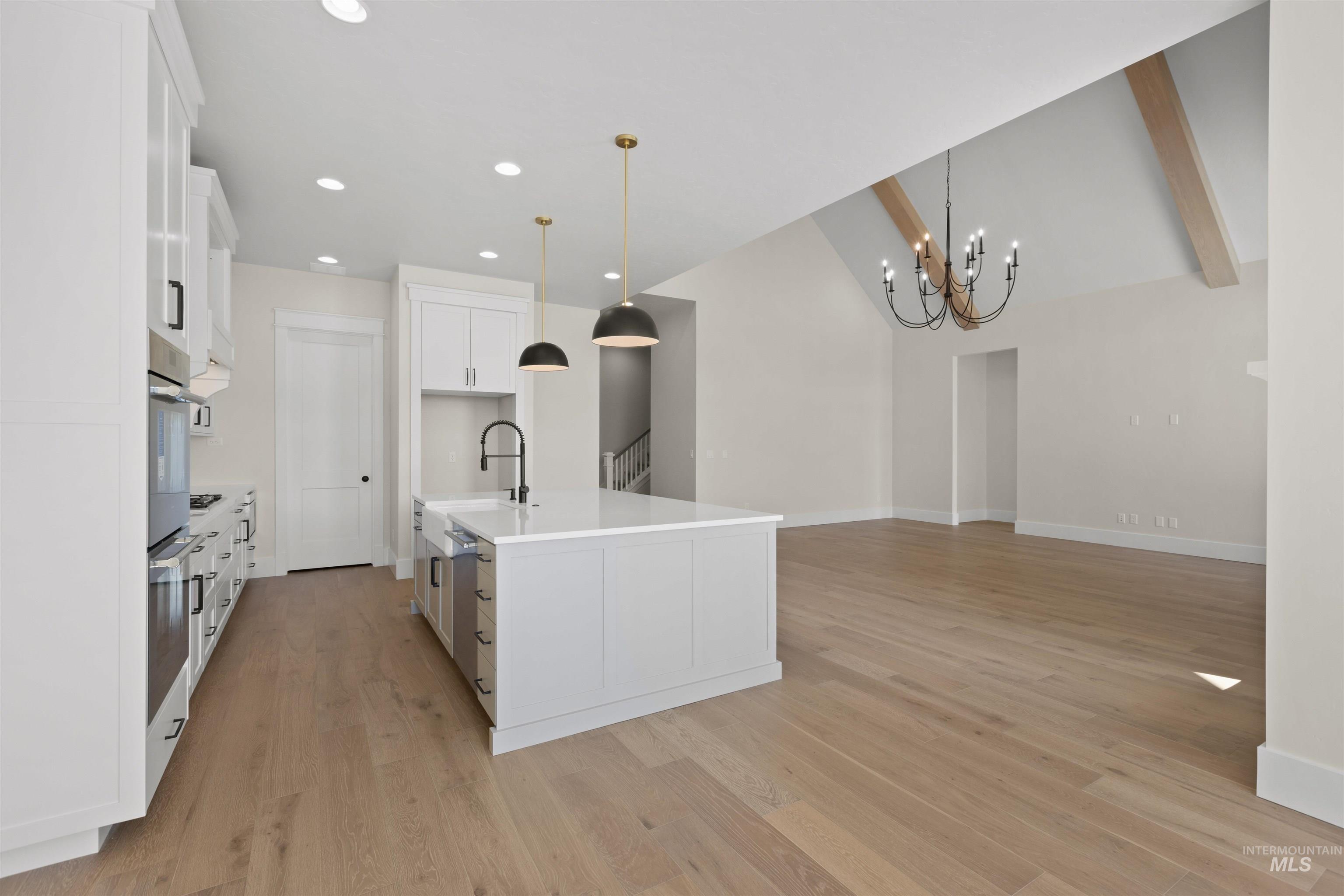 Kitchen with a chandelier, light wood-style floors, white cabinets, recessed lighting, and light countertops